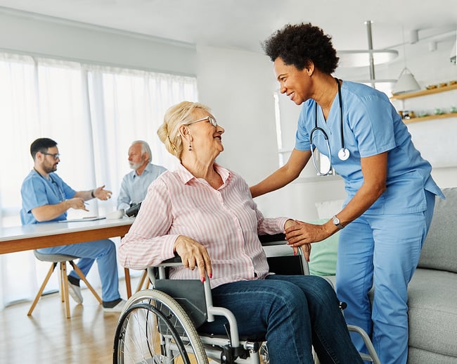 medical assistant smiling while speaking to a happy elderly female patient in a wheelchair