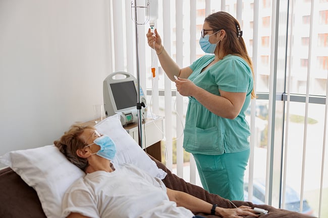 Nurse monitoring a patient in a hospital room.