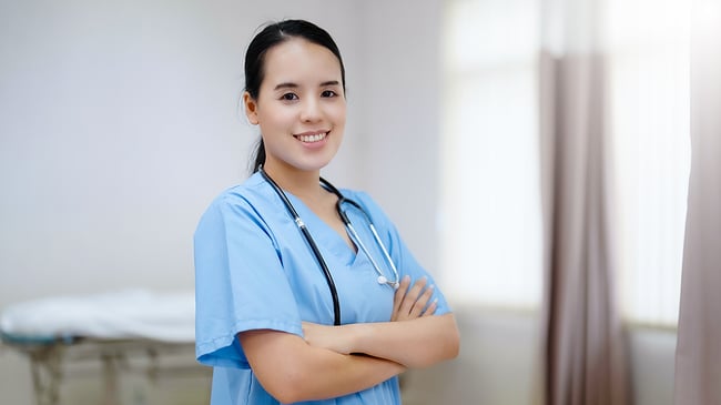 Medical assistant smiling against a window.