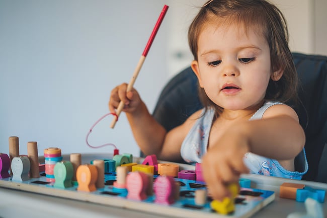 little girl playing with toys at a table