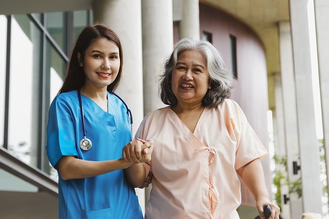 young female medical assistant helping a hosputal patient on a walk