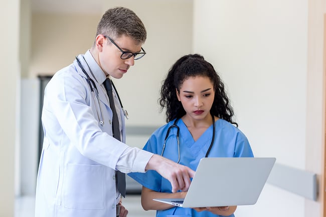 male doctor and female medical assistant viewing information on a laptop