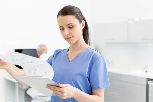 Medical student looking at paperwork on a clipboard.