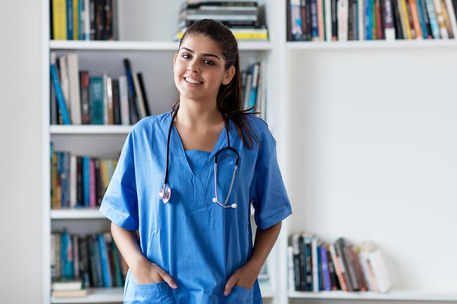 Medical assistant standing in front of a bookcase.