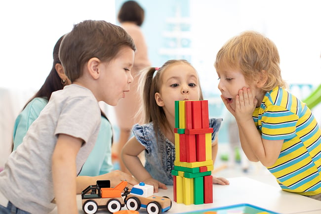 Young students playing with blocks in a preschool classroom.