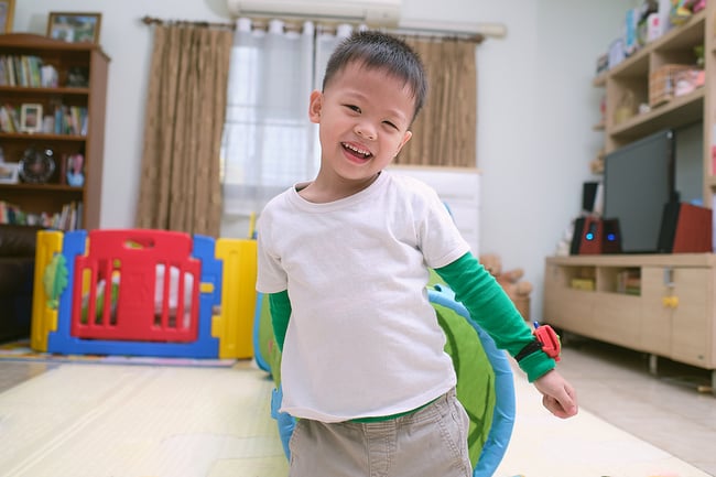 Smiling preschool student standing in a colorful classroom.