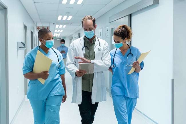 Medical assistants walking through a medical facility hallway with a doctor.