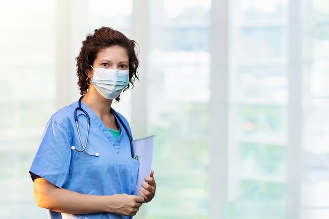 Medical assistant wearing a surgical mask holding a medical file.