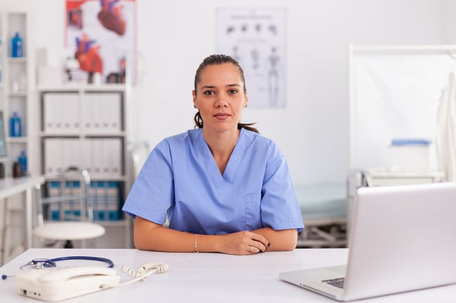Medical assistant sitting at a desk with a laptop.