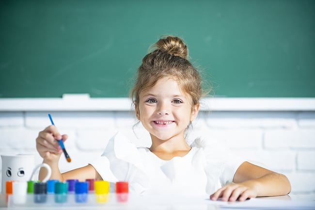 Young girl painting in a preschool classroom.