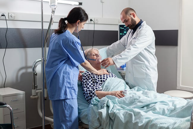 Nurse and doctor helping a patient who is lying in bed.