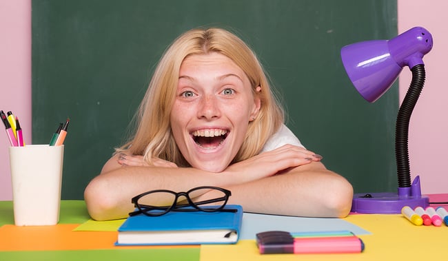 Young teacher sitting at her desk with a surprised look on her face.